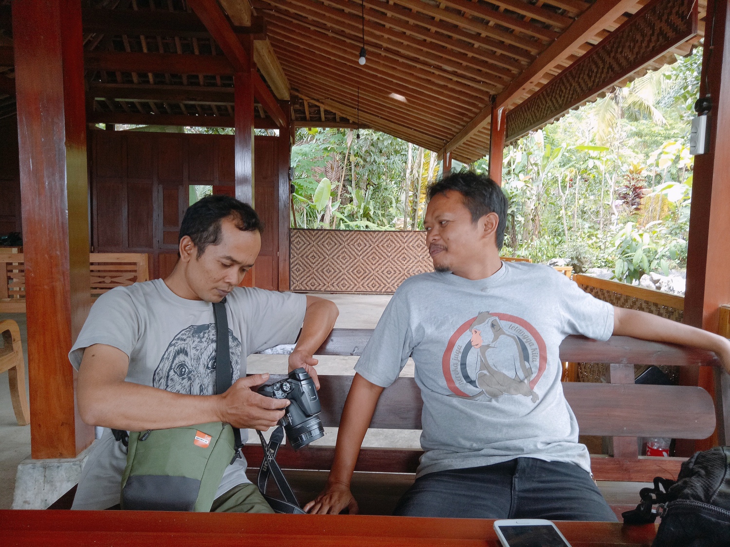 Suparno (left) and Arif take a break and review photographs of Jatimulyo’s birds.