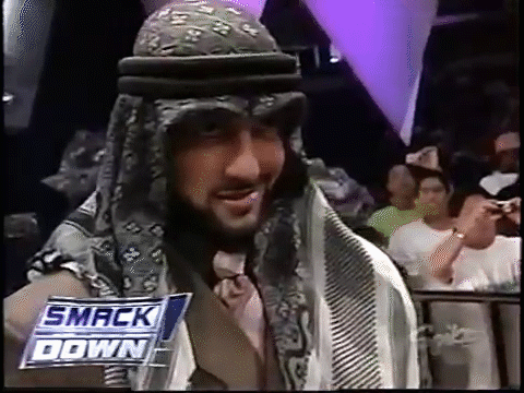 A gif of Muhammad Hassan, a wrestler who portrays an Arab American person as his wrestler persona laughing menacingly before sending five 'terrorists' to the ring