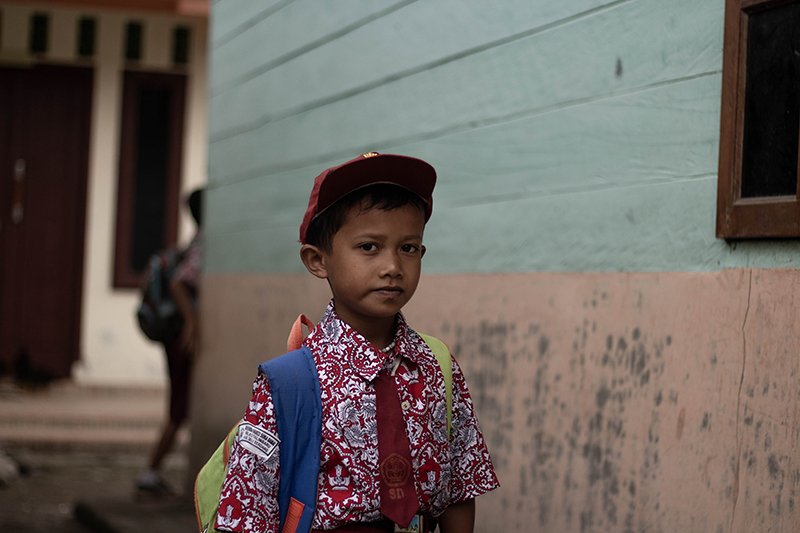 A primary school boy wearing a state school uniform that is consists of a batik top.